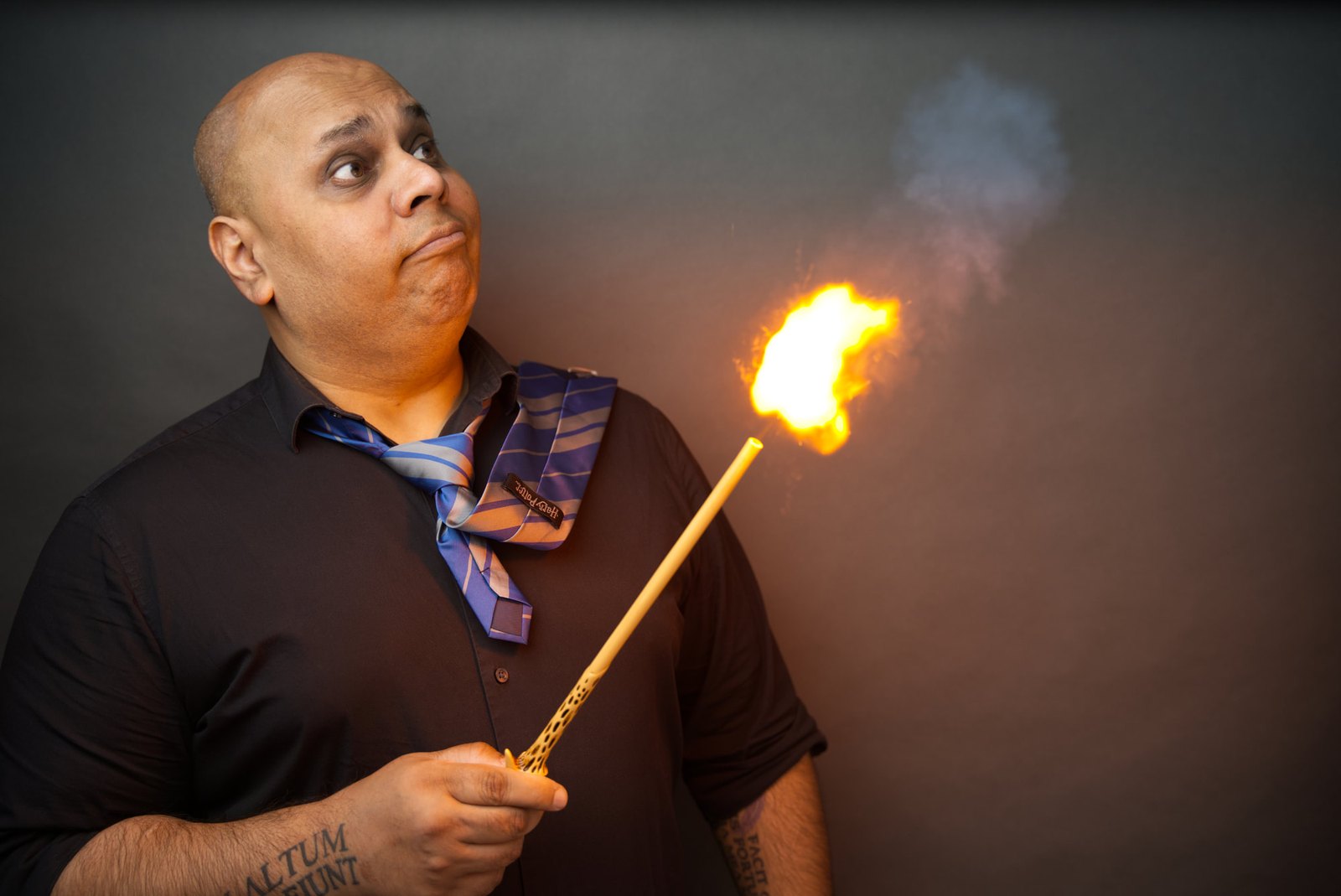 Cash performing a Hogwarts magic show for kids, lighting a wand in a Hogwarts house tie